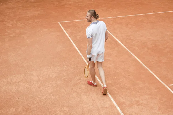 Handsome tennis player with racket on brown court — Stock Photo