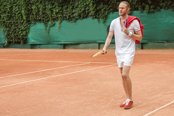 Schöner Mann in Sportbekleidung mit Retro-Holzschläger auf dem Tennisplatz — Stockfoto