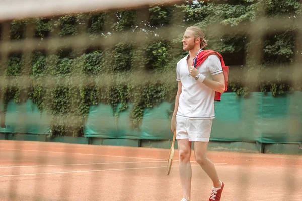 Enfoque selectivo del jugador de tenis con raqueta a través de la red - foto de stock