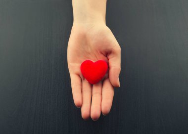 Küçük kırmızı kalbi tutan bir kadın.