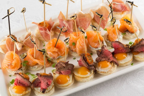 Aperitivo festivo con huevo de codorniz, salmón y rosbif —  Fotos de Stock