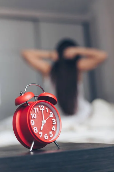 Primer plano despertador con fondo mujer feliz estiramiento en la cama después de —  Fotos de Stock