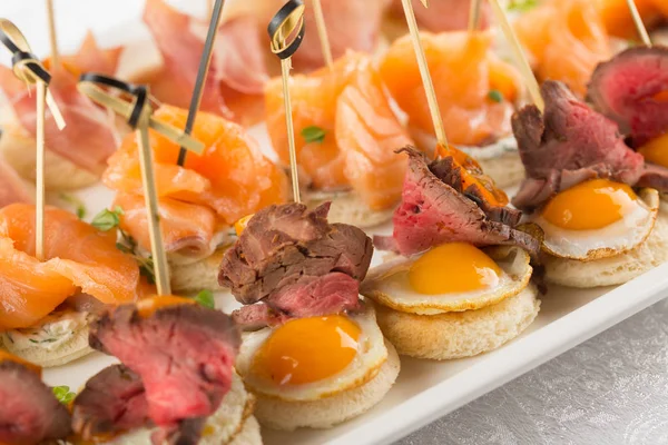 Aperitivo festivo con huevo de codorniz, salmón y rosbif — Foto de Stock