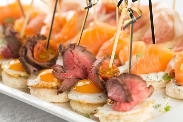 Aperitivo festivo com ovo de codorna, salmão e rosbife — Fotografia de Stock