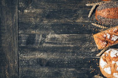 Kahverengi ve beyaz ekmekler, tahta arka planda dikenli dikenler ve fotokopi alanı. Üç farklı tür ekmek. Fırın, aşçılık ve bakkal konsepti