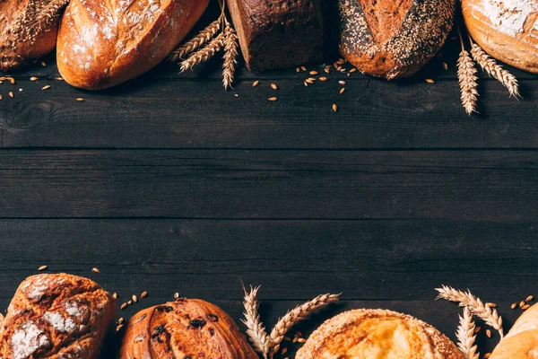 Borde de pan sobre fondo de madera con espacio para copiar. Diferentes tipos de pan dispuestos como marco con espiguillas. Panadería, cocina y concepto de tienda de comestibles . —  Fotos de Stock