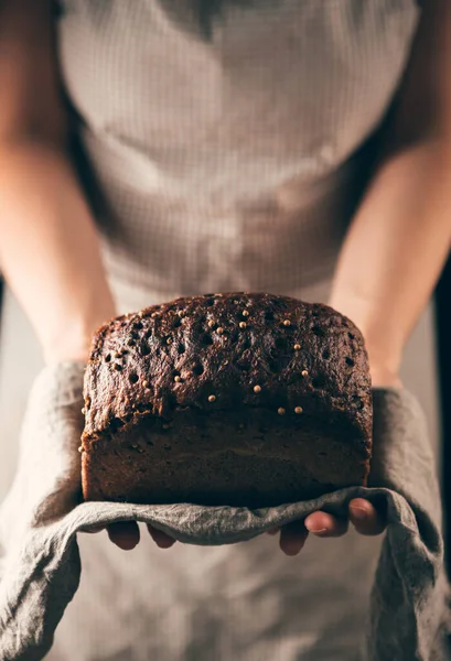 Havlunun üzerinde çavdar ekmeği tutan kadın elleri. Fırın posteri veya kapağı kavramı
