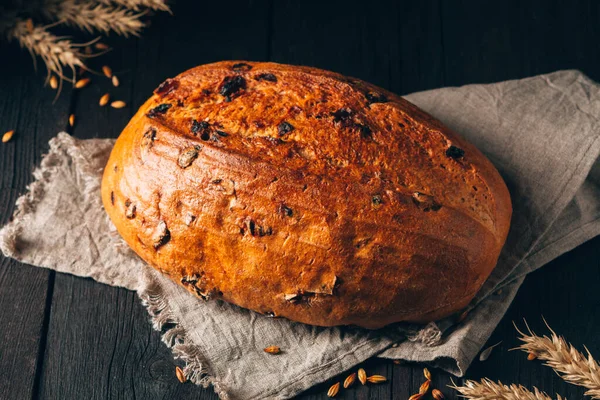 Siyah ahşap arka planda tekstil havlusunda kuru üzümlü kahverengi ekmek. Telifsiz Stok Imajlar