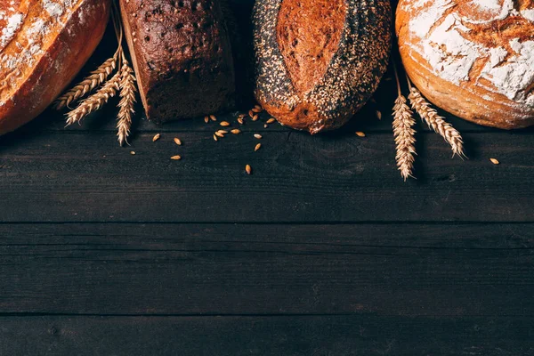 Borde de pan sobre fondo de madera oscura con espacio para copiar. Diferentes tipos de pan. Panadería, cocina y concepto de tienda de comestibles . — Foto de Stock
