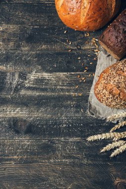 Ahşap zemin üzerinde kopyalama alanı olan ekmek kenarlığı. Bir köşede farklı türde ekmek. Fırın, aşçılık ve bakkal konsepti.