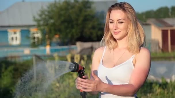 Jeune femme blonde arrosant un jardin . — Video