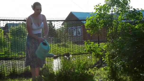 Glad Kvindelige Gartner Vand Planter og Blomster med en vandkande i Sunny Garden . – Stock-video