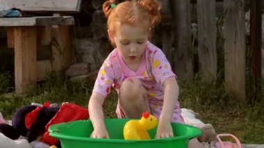 Çocuk bir leğen su ile sarı lastik ördek ile oynuyor. Backyerd içinde