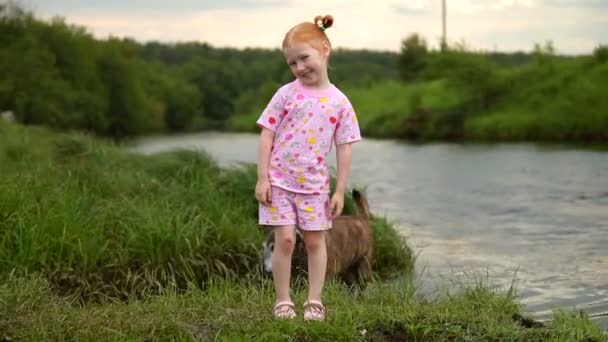 Red-Haired Girl Walking With a Dog on the River. Smile on camera — Stock Video