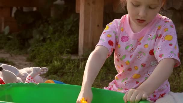 L'enfant joue avec des jouets dans un bassin avec de l'eau — Video