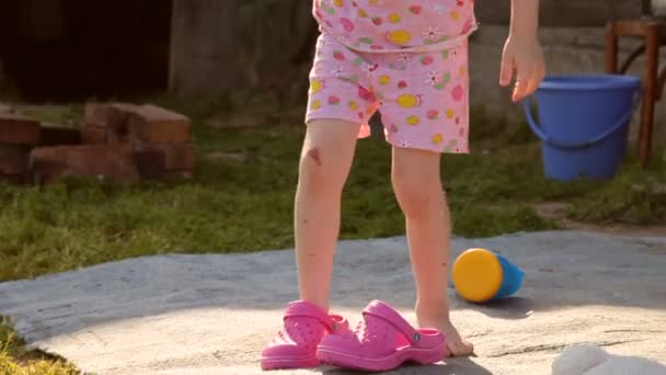 The Child is Being Trained. Learns to Dress Shoes Above Garden — Stock Video