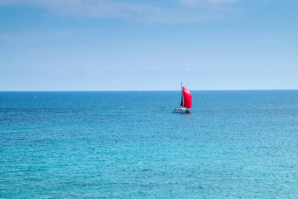 Red ship on red sails. Blue sea and sky.