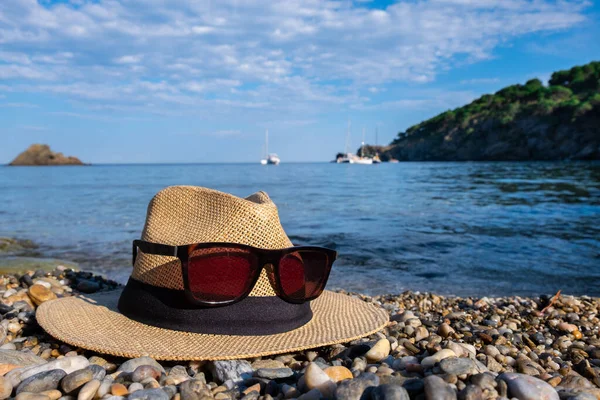 Närbild av en hatt och solglasögon. Blått hav och himmel. — Stockfoto