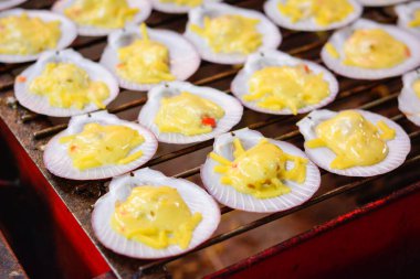 Mangalda ızgara deniz tarağı, tereyağı ve peynirli ızgara deniz tarağı Tayland deniz ürünleri, Tayland 'da ızgara deniz tarağı satışı, tereyağı ve sarımsaklı ızlı ızgara deniz tarağı.