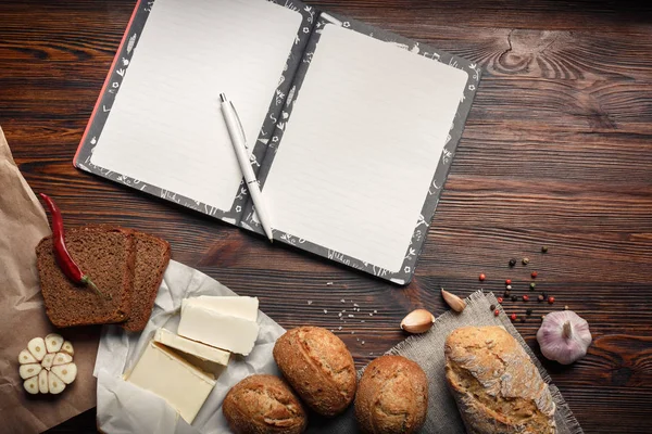 Petrol, ekmek, biber, sarımsak ve Not defteri bir kahverengi ahşap tahta üzerinde bir dizi