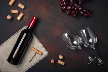 Şişe şarap, iki bardak, kırmızı üzüm, tirbuşon ve paslı arka plan üstten görünüm, kopya alanı tarihinde mantarlar