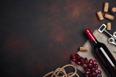 Şişe şarap, kırmızı üzüm, tirbuşon ve paslı arka plan üstten görünüm, kopya alanı tarihinde mantarlar