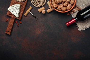 Şişe şarap, mavi peynir, ceviz, badem, tirbuşon, ip ve paslı arka plan üstten görünüm tarihinde mantarlar