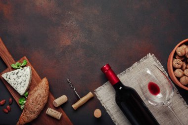 Şişe şarap, mavi peynir, ceviz, badem, tirbuşon, ip ve paslı arka plan üstten görünüm tarihinde mantarlar