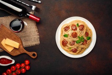Spagetti makarna köfte, peynir, kiraz domates sosu, bardağı ve paslı arka planda, üstten görünüm şarap şişe