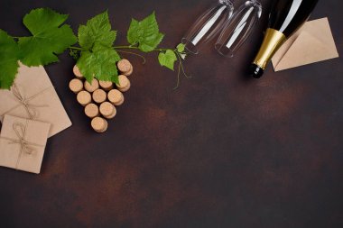 Şişe şampanya, esnemek demet yaprak, iki bardağı ve zarf paslı arka plan üstten görünüm üzerinde mantar.