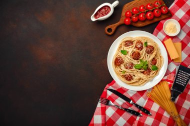 Spagetti makarna köfte, kiraz domates sos ve peynir paslı arka planda, üstten görünüm.