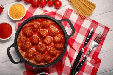 Baharat beyaz ahşap tahta üzerinde bir tavada domates soslu levrek. Üstten görünüm.