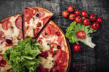 Pizza jambon, salam, peynir, mantar, domates, biber ve salata siyah tebeşir tahtası, üstten görünüm.