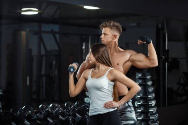Spor, eğitim, spor, yaşam tarzı ve insanlar kavramı - kişisel antrenör bel ve karın kasları spor salonunda bankta esneme ile genç kadın.