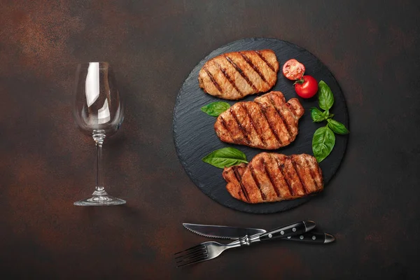 Grilované Vepřové Steaky Bazalkou Rajčaty Nůž Vidlička Sklenice Víno Černý — Stock fotografie