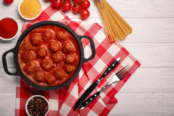 Baharat beyaz ahşap tahta üzerinde bir tavada domates soslu levrek. Üstten görünüm.