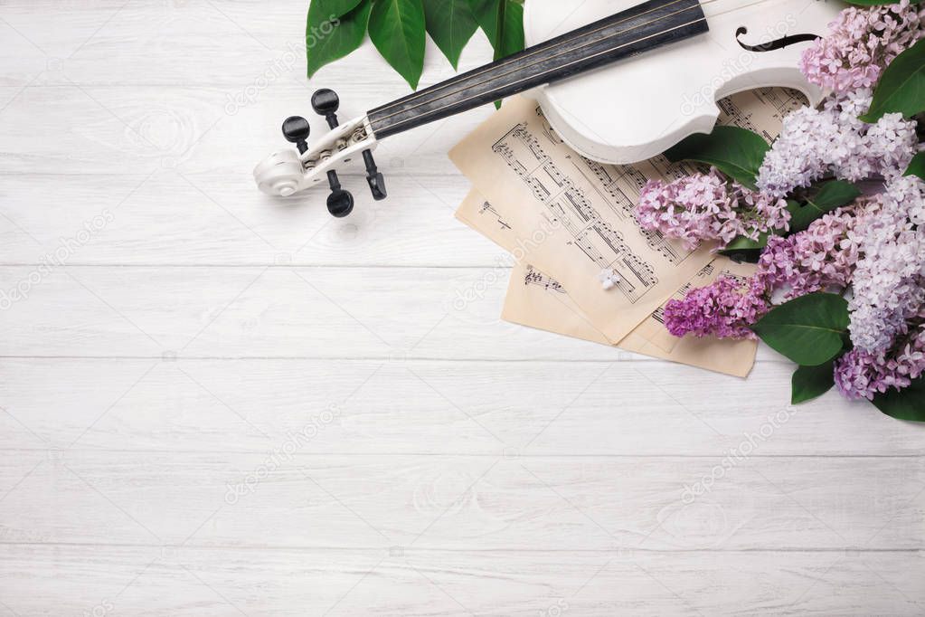 A bouquet of lilacs with violin and music sheet on a white wooden table. Love spring background. Top wiev with space for your text.