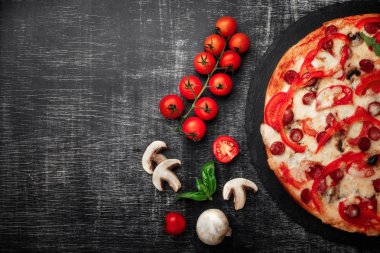 Pizza Tütsülenmiş sosis, peynir, mantar, domates, biber ve yeşillik bir taş ve bir siyah tebeşir yönetim kurulu, sizin metin için yer ile üstten görünüm.