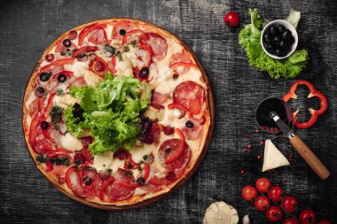 Pizza jambon, salam, peynir, mantar, domates, biber ve salata siyah tebeşir tahtası, üstten görünüm.