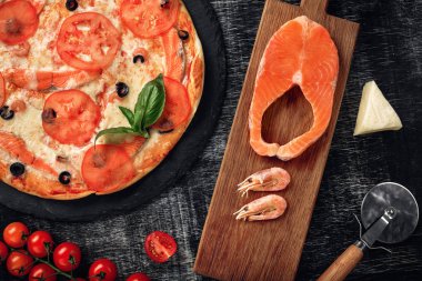 Pizza peyniri, alabalık, domates, zeytin ve karides tebeşir yönetim kurulu, üstten görünüm.