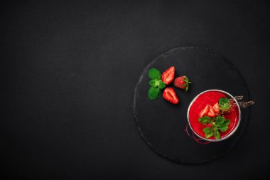 Çilekli tatlı mousse krema, karamel ve nane taş ve siyah arka plan ile. Metin alanı olan üstten görünüm.