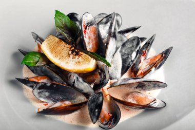 Limon ve beyaz bir tabak içinde fesleğen krema soslu deniz mahsulleri midye. Üstten görünüm .