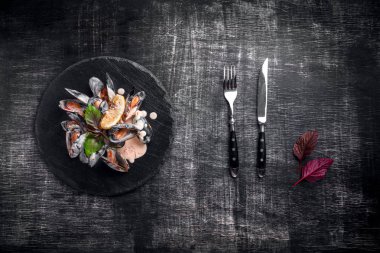 Limon ve fesleğen bir taş ve kara tahta üzerinde krema soslu deniz mahsulleri midye. Üstten görünüm.