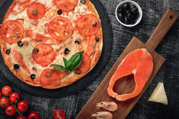 Pizza peyniri, alabalık, domates, zeytin ve karides tebeşir yönetim kurulu, üstten görünüm.