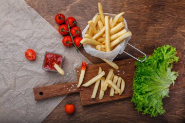Ketçap, salata ve domates ahşap kahverengi masa üzerinde bir kılavuzda patates kızartması. Üstten görünüm.