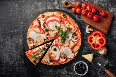 Peynir, jambon, salatalık turşusu, et ve bir taş ve bir siyah tebeşir tahtası, üstten görünüm zeytin pizza.