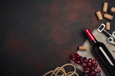 Şişe şarap, kırmızı üzüm, tirbuşon ve paslı arka plan üstten görünüm, kopya alanı tarihinde mantarlar