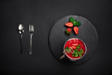 Çilekli tatlı mousse krema, karamel ve nane taş ve siyah arka plan ile. Üstten görünüm.