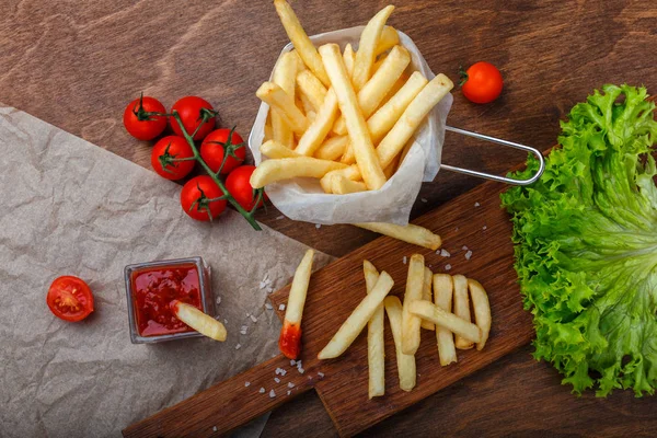 Ketçap, salata ve domates ahşap kahverengi masa üzerinde bir kılavuzda patates kızartması. Üstten görünüm.