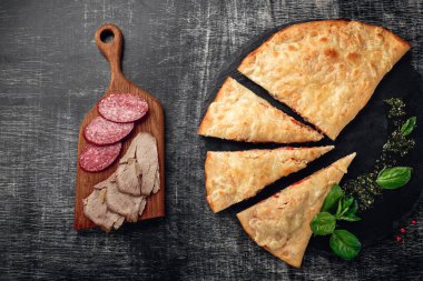 Geleneksel İtalyan pizza calzone bir taş ve koyu ahşap malzemelerle arka plan kaşıdı. Üstten görünüm.